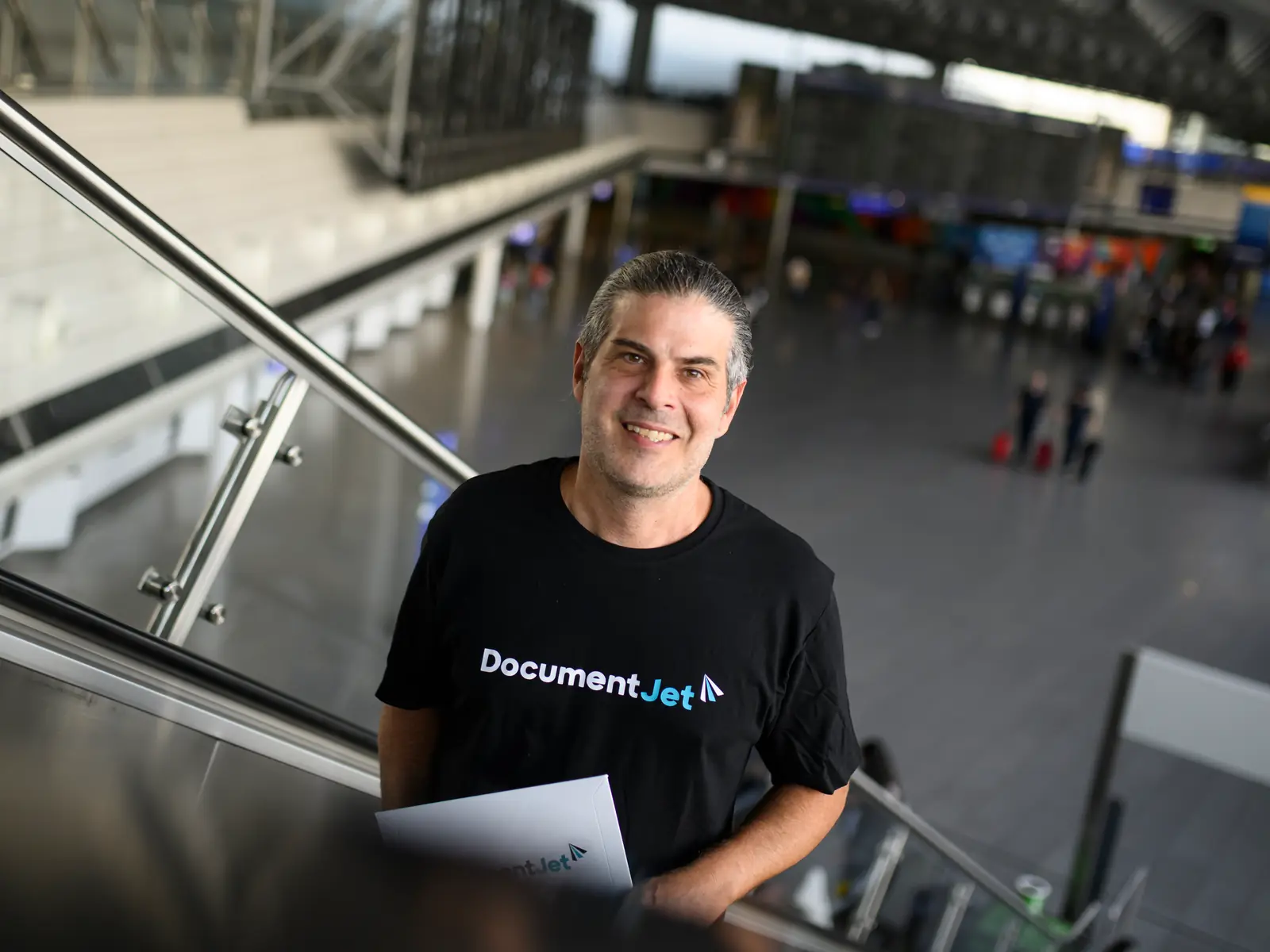 Mensajero aéreo de DocumentJet en una escalera mecánica de la terminal de un aeropuerto